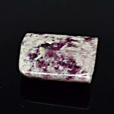 A piece of purple stone on a black surface.
