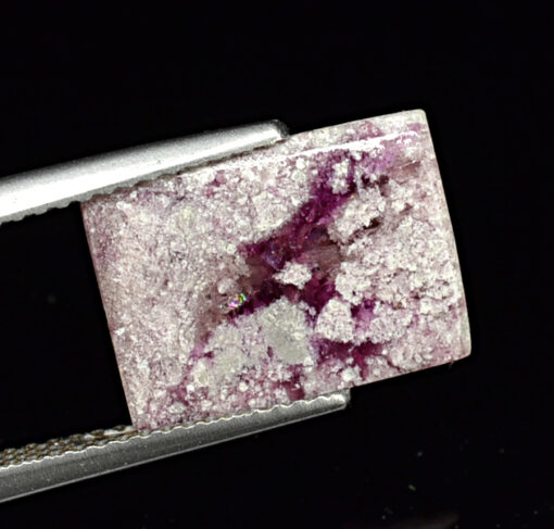 A pink and white stone is being held by a pair of pliers.