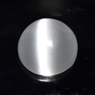 A white ball sitting on a black surface.