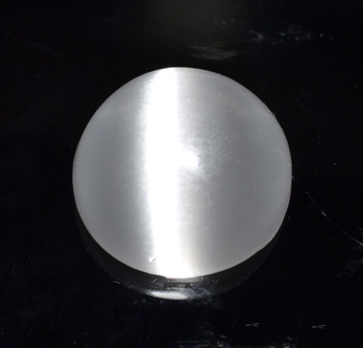 A white ball sitting on a black surface.