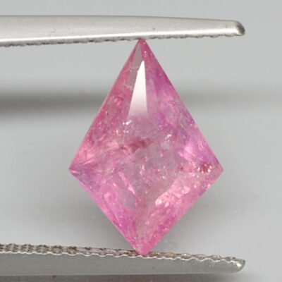 A pink sapphire is being held by a pair of pliers.