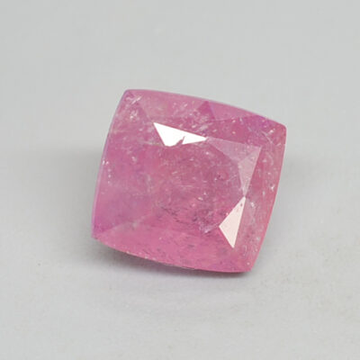 A pink sapphire stone on a white surface.