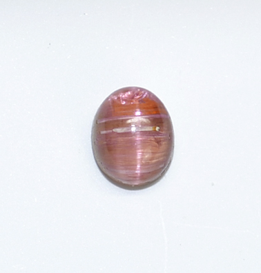 An oval shaped pink glass bead on a white surface.