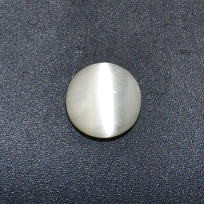 A round white stone on a black surface.