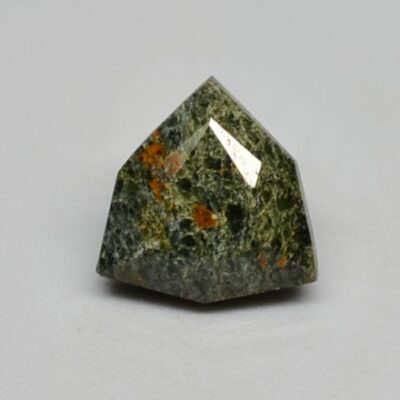 A green stone with orange spots on it.