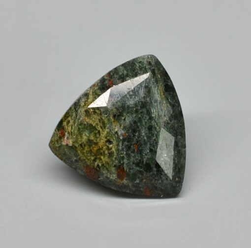 A green jade stone on a gray surface.