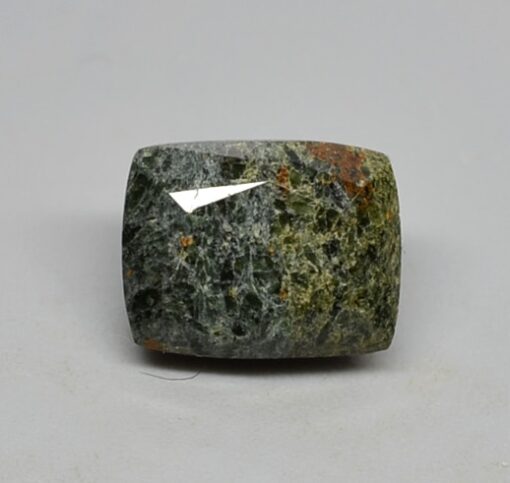 A green jade stone on a white surface.