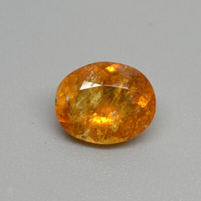 An orange sapphire stone on a white surface.