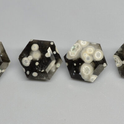 A group of black and white hexahedral cabochons on a gray surface.