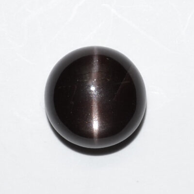 A round black stone on a white surface.