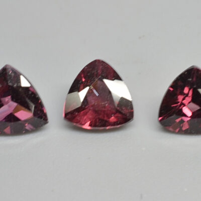 Three pink sapphires on a white surface.