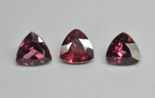 Three pink sapphires on a white surface.