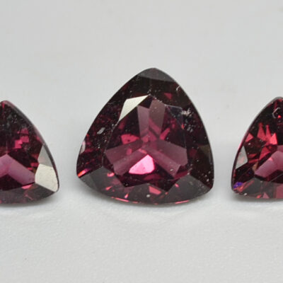 Three pear shaped pink sapphires on a white surface.