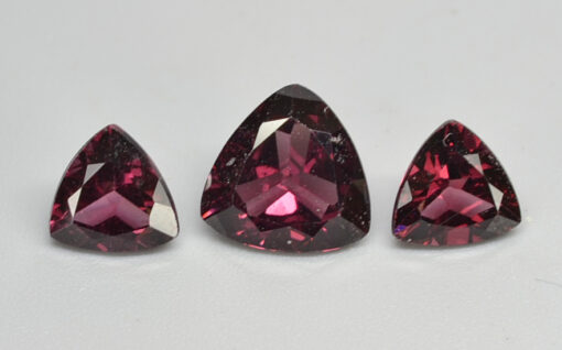 Three pear shaped pink sapphires on a white surface.