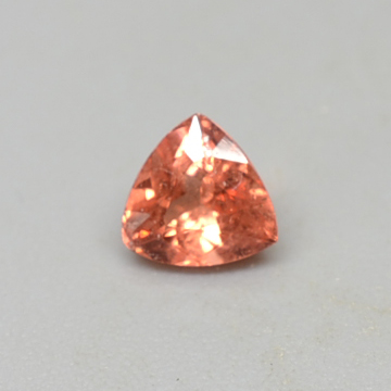 A natural orange sapphire cut into a triangular shape.
