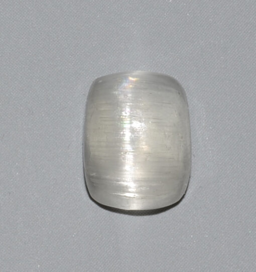 A white quartz cabochon on a gray surface.