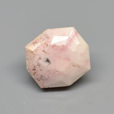 A piece of pink quartz on a gray surface.